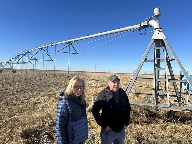 Gina and Marc Gigot stand in front of a center pivot irrigation system on their farm outside of Garden City, Kansas. The farm has historically been among the largest water users in Kansas, but it has cut usage in recent years as part of voluntary conservation measures aimed at slowing the decline of the Ogallala Aquifer. (Photo by Kevin Hardy/Stateline)